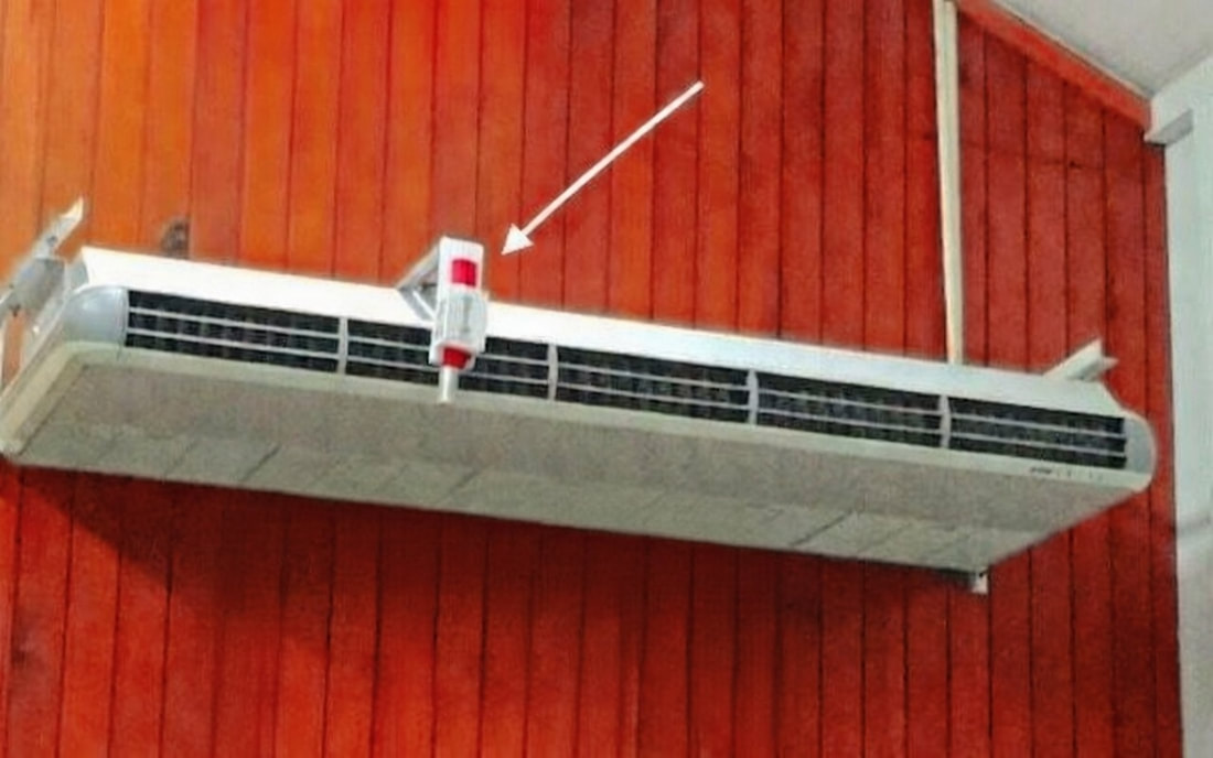 PurAire SG-Mini-5 bipolar ioniser fitted inside a wall-mounted split air conditioner, arrow indicating the unit position